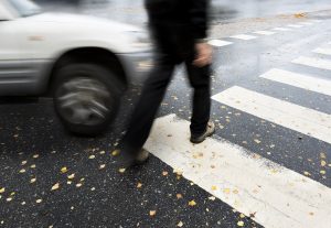 Photo of a man in a cross walk about to get hit by a car